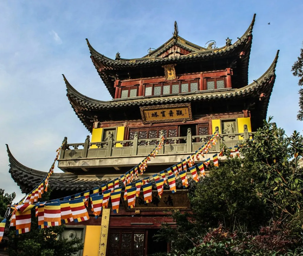 A traditional Chinese temple with ornate architecture and colorful prayer flags displayed.