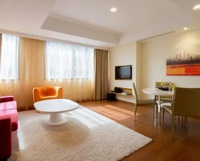 A modern living space with bright furniture, wood flooring, and large windows for natural light.