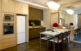 Modern kitchen and dining area with sleek cabinetry, elegant lighting, and a mirrored wall.