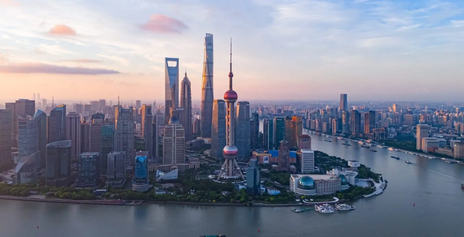 Shanghai skyline at sunset, featuring the Oriental Pearl Tower and modern skyscrapers.