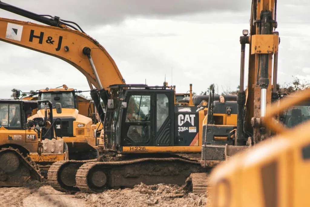 Yellow construction equipment, including excavators and loaders, operating on a dirt site.