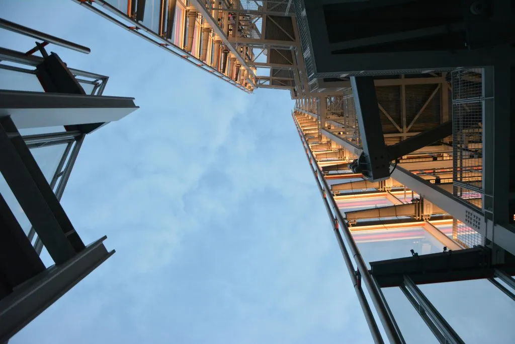 Upward view of modern steel and glass architecture against a cloudy blue sky.