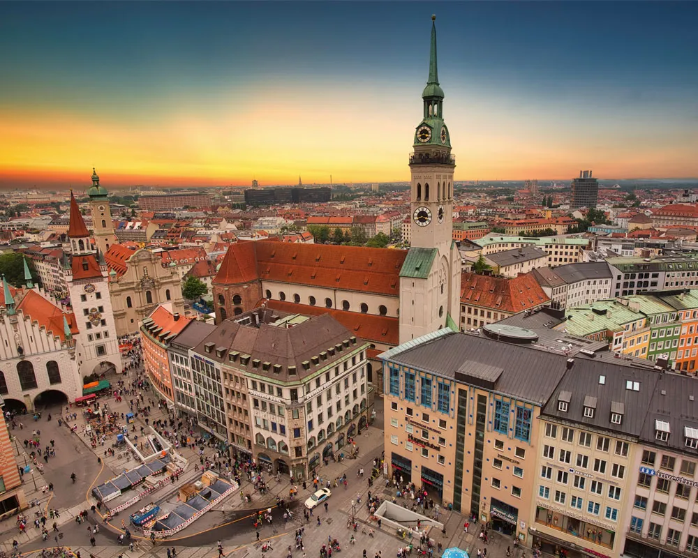A vibrant cityscape of Munich's Marienplatz with historic architecture at sunset.