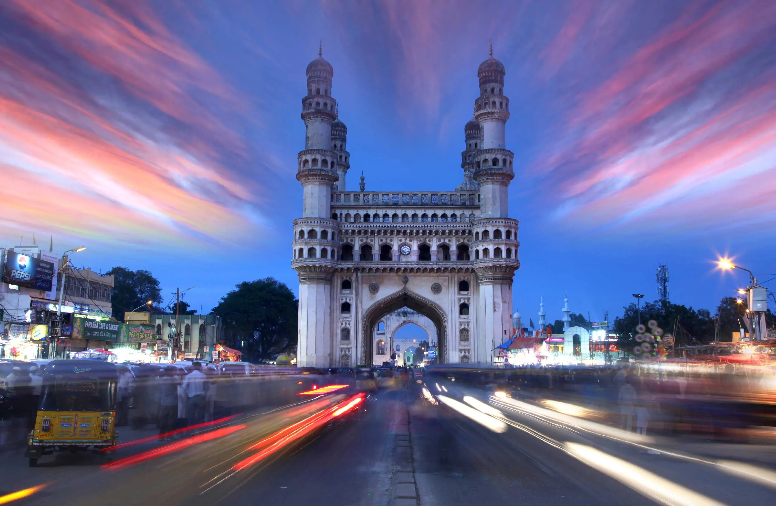 Charminar in Hyderabad at dusk, surrounded by vibrant lights and bustling street activity.