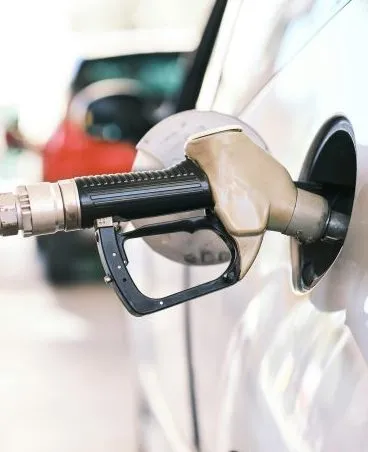 A fuel pump nozzle inserted into a vehicle's gas tank at a refueling station.