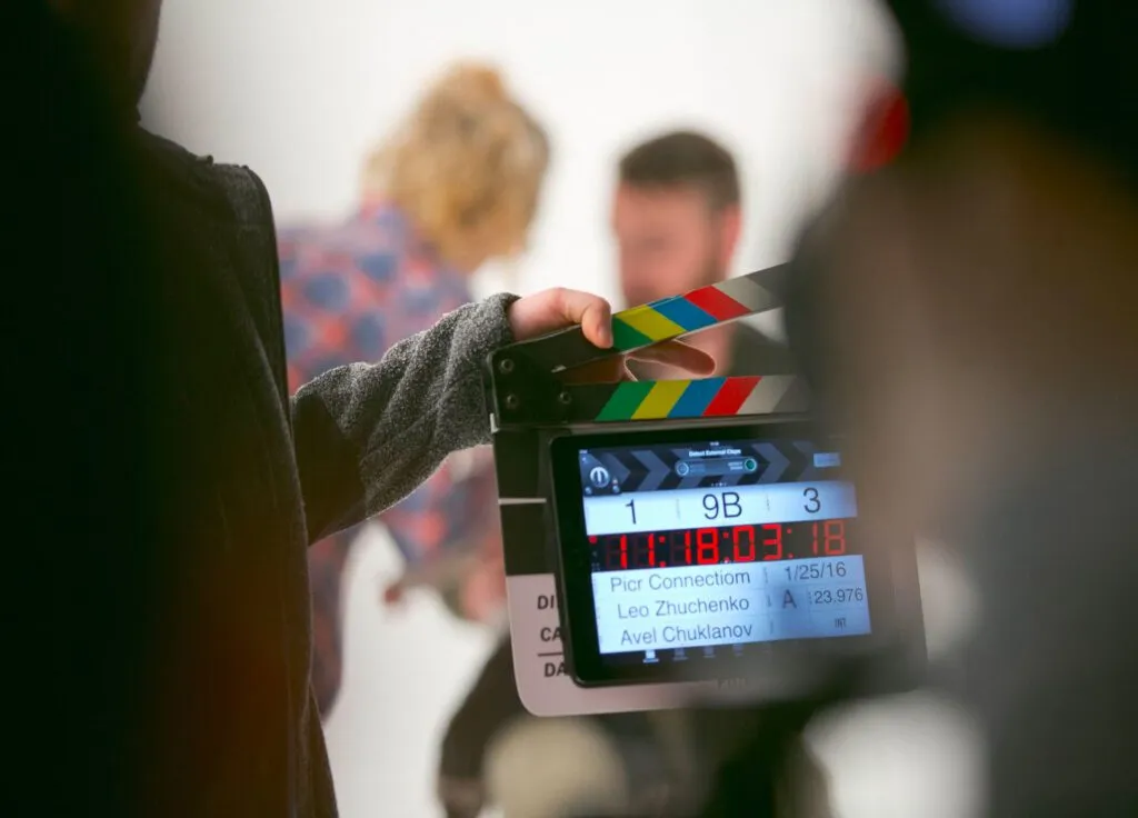 A film clapperboard is held on set, indicating scene details and marking the start of a take.