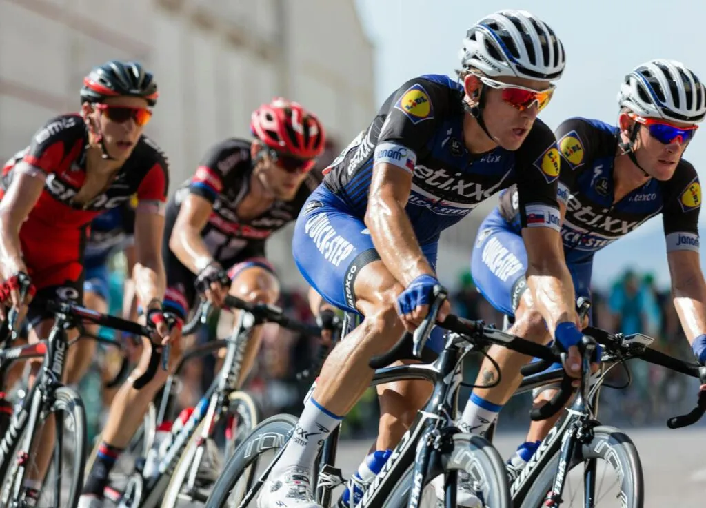 Cyclists in professional gear race closely together on a sunny day, showcasing intense competition.