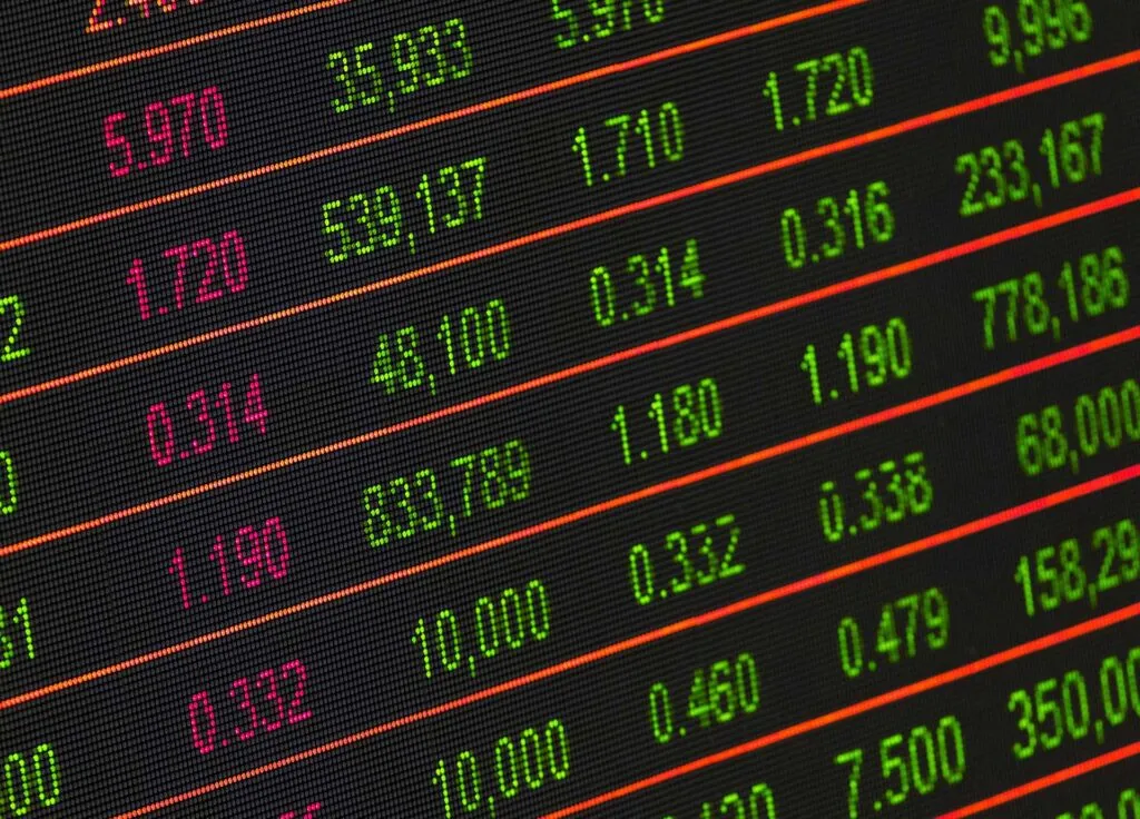 Stock market data displayed with numerical values in green and red on a digital screen.