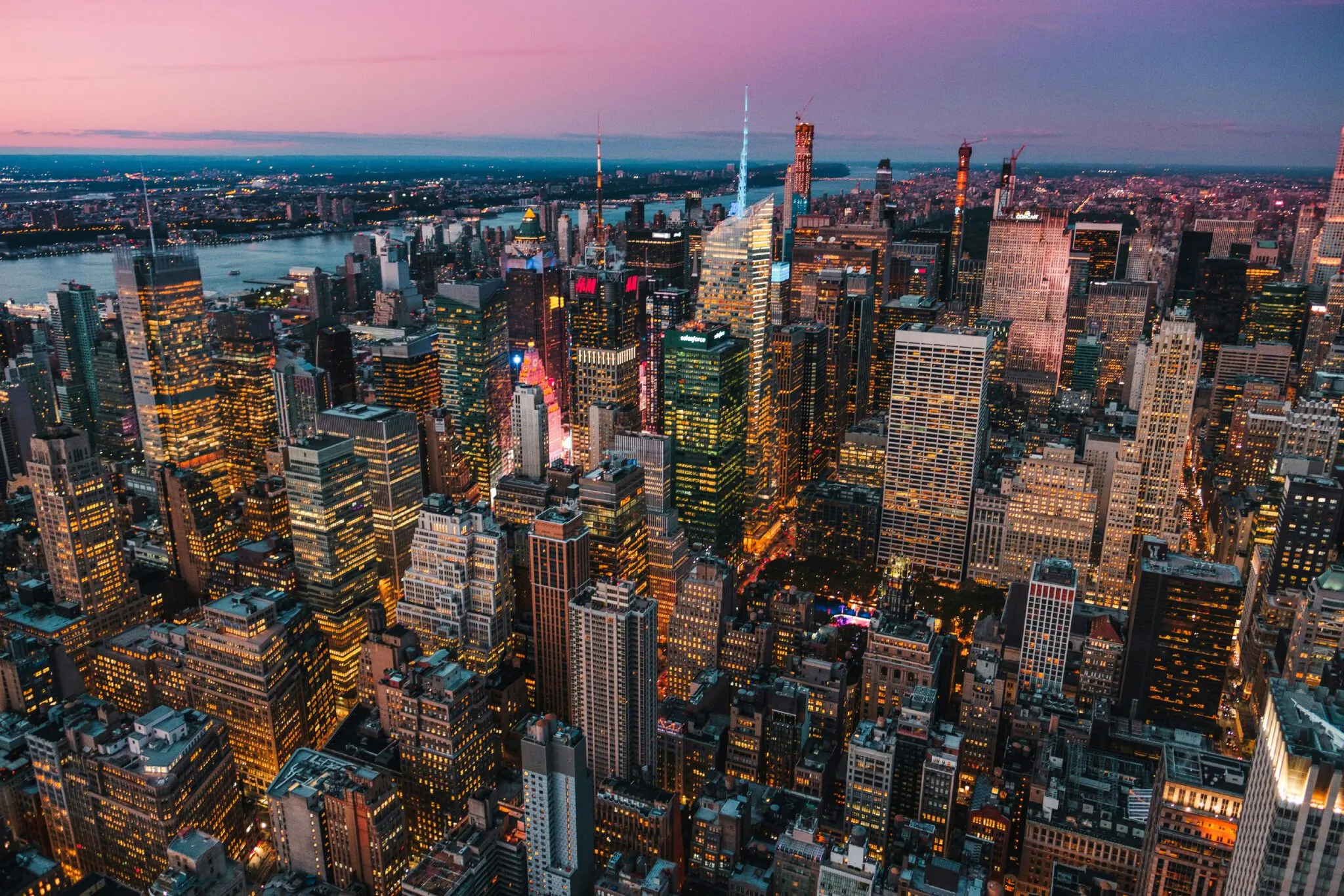 A vibrant cityscape at dusk, showcasing illuminated skyscrapers and a colorful sky.