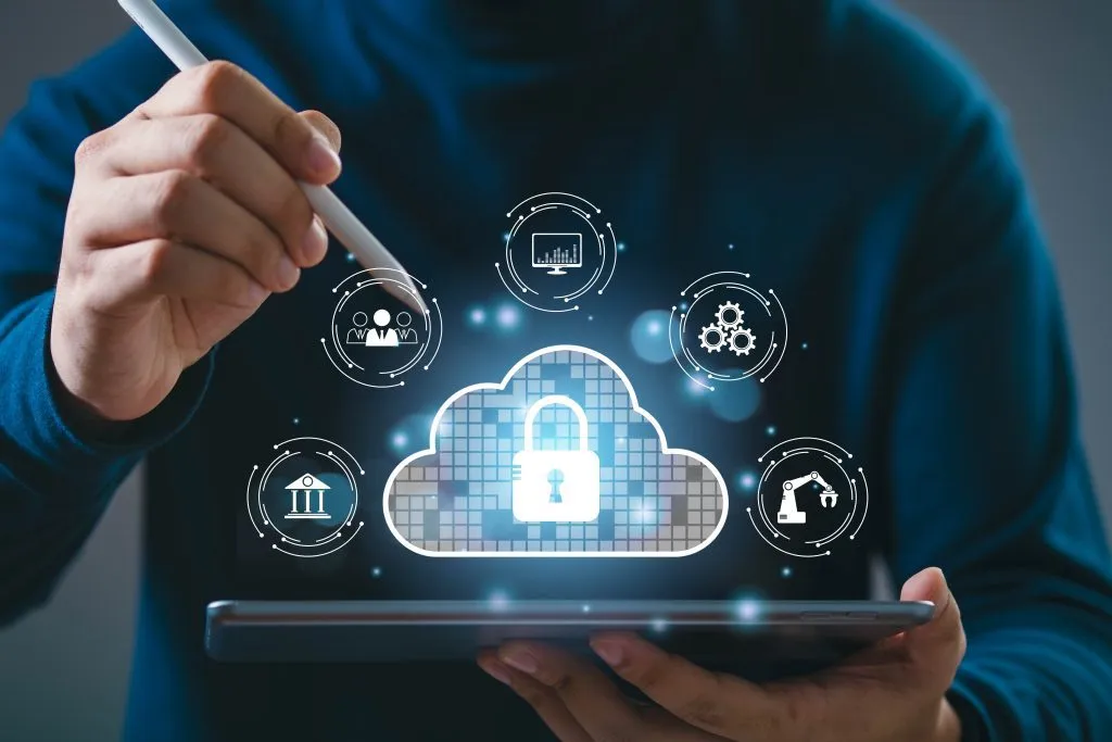 A person interacts with a tablet displaying cloud security and digital transformation icons.