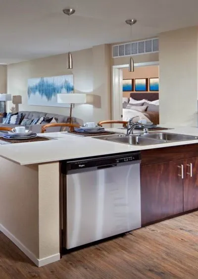 Modern open-concept kitchen with stainless steel appliances and a view into the living and bedroom areas.