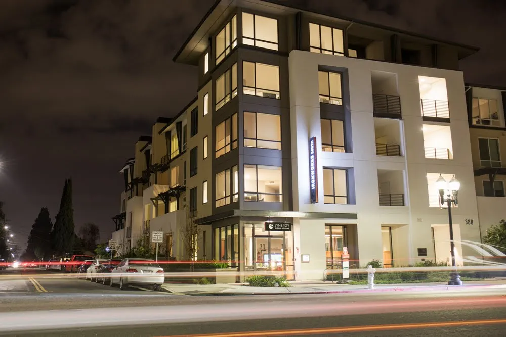 Modern multi-story building with illuminated windows and signage at night.