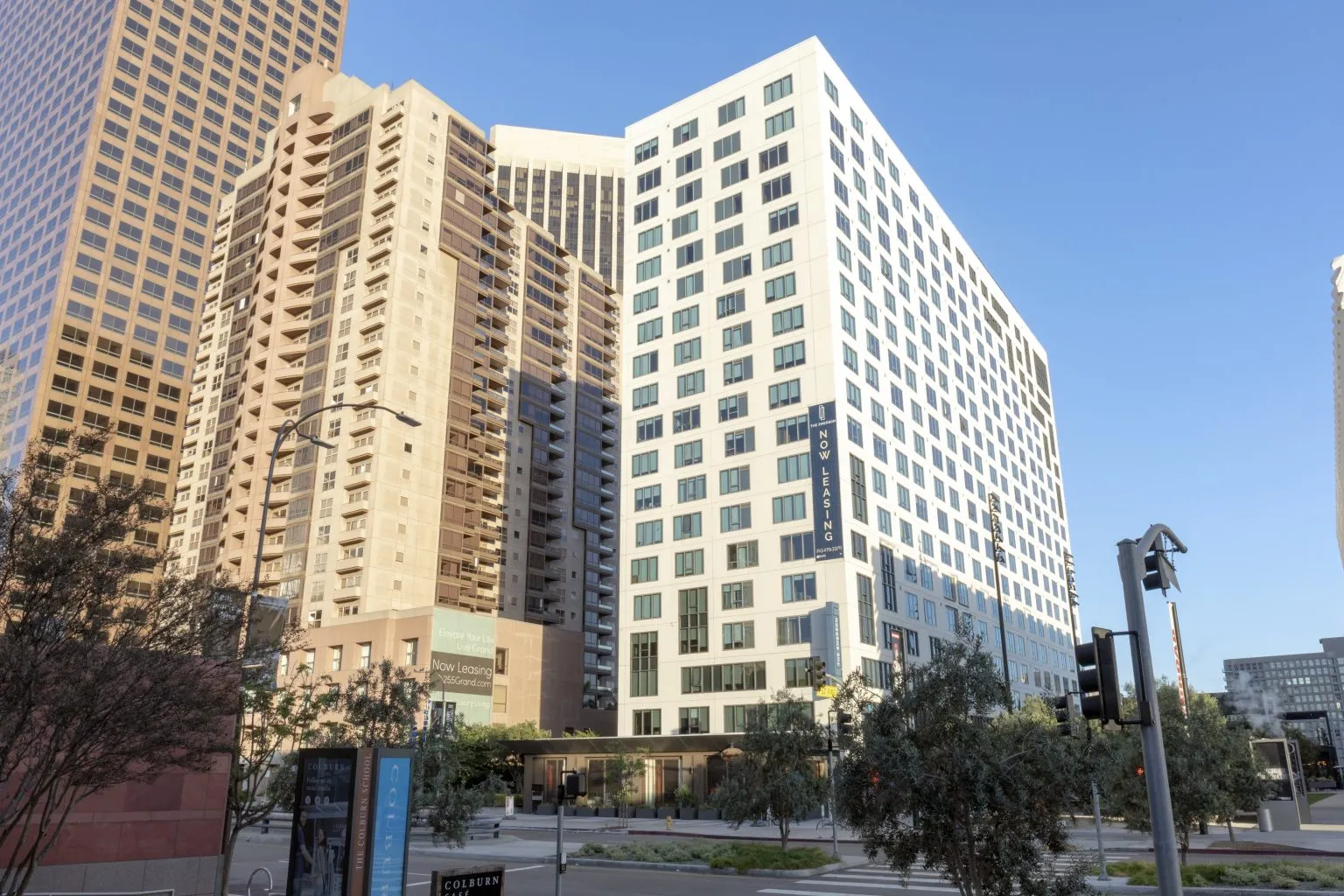 Modern high-rise buildings with a "Now Leasing" sign in an urban downtown setting.