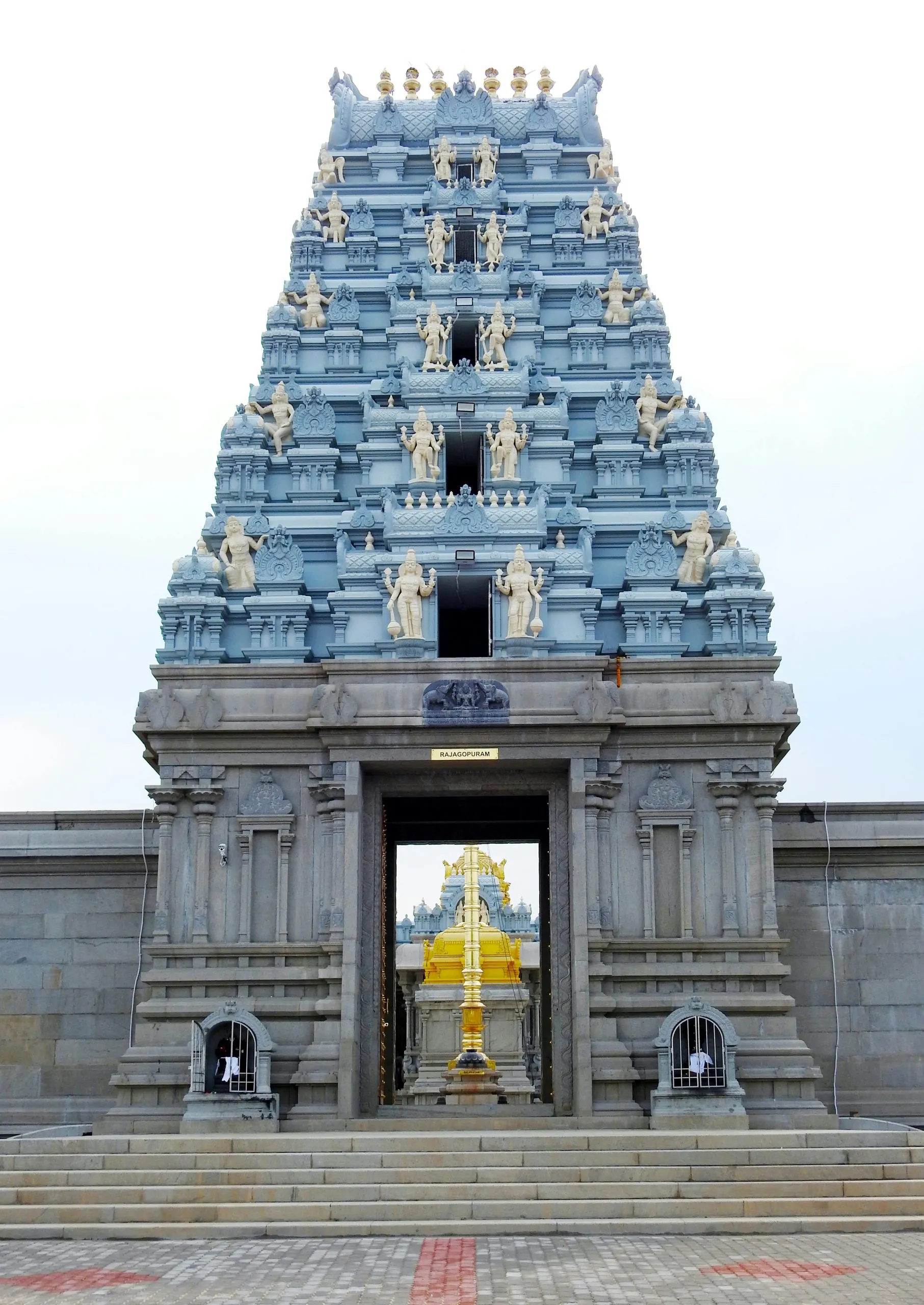 A traditional South Indian temple gopuram with intricate carvings and a golden structure inside.