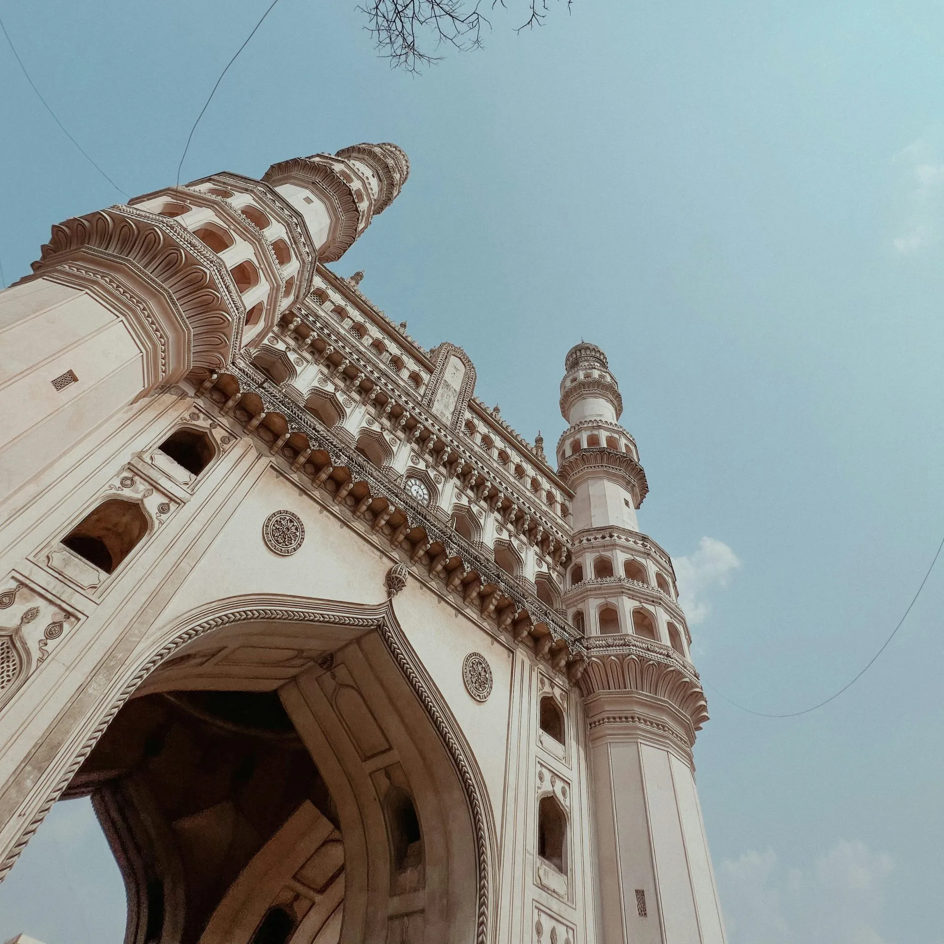 Charminar's intricate architecture with towering minarets under a clear blue sky.