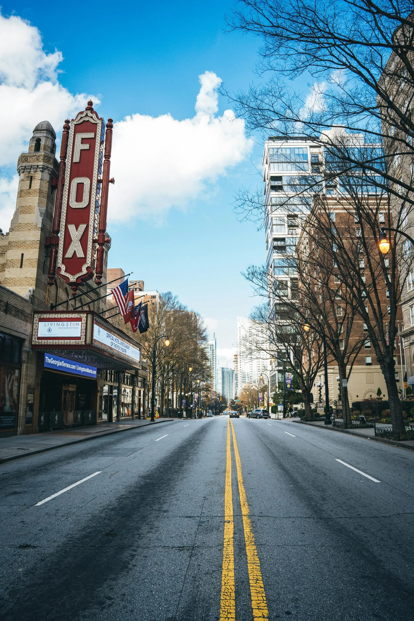 Street view of Atlanta's Fox Theatre, flanked by trees and modern buildings under a clear sky.