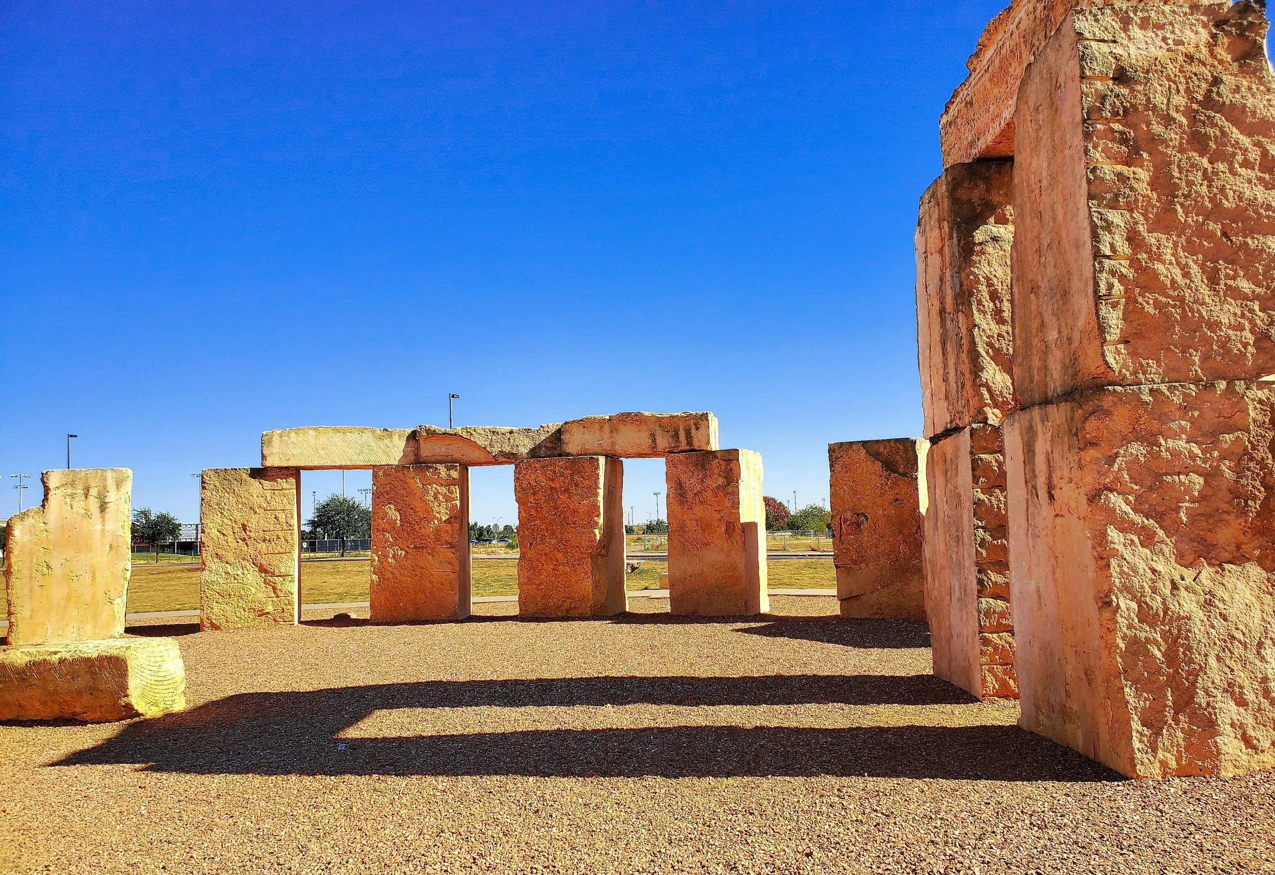 Stonehenge replica with large limestone blocks under a clear blue sky in a grassy open area.