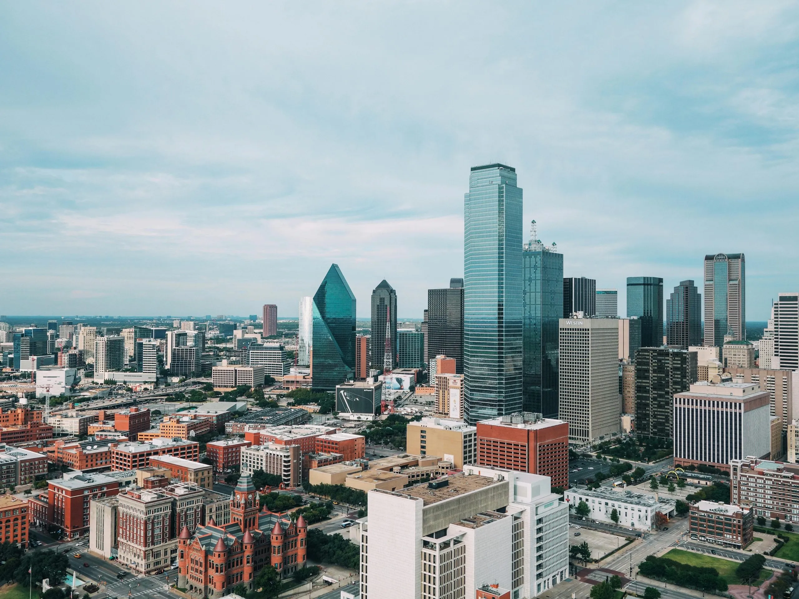 Dallas skyline featuring modern skyscrapers and historic architecture under a cloudy sky.