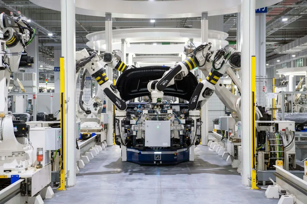Robotic arms assemble a vehicle in a modern, automated manufacturing facility.