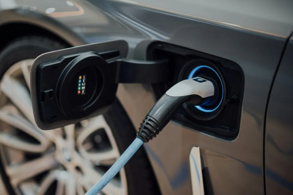 Electric vehicle charging port with a connected charging cable, highlighting clean energy technology.