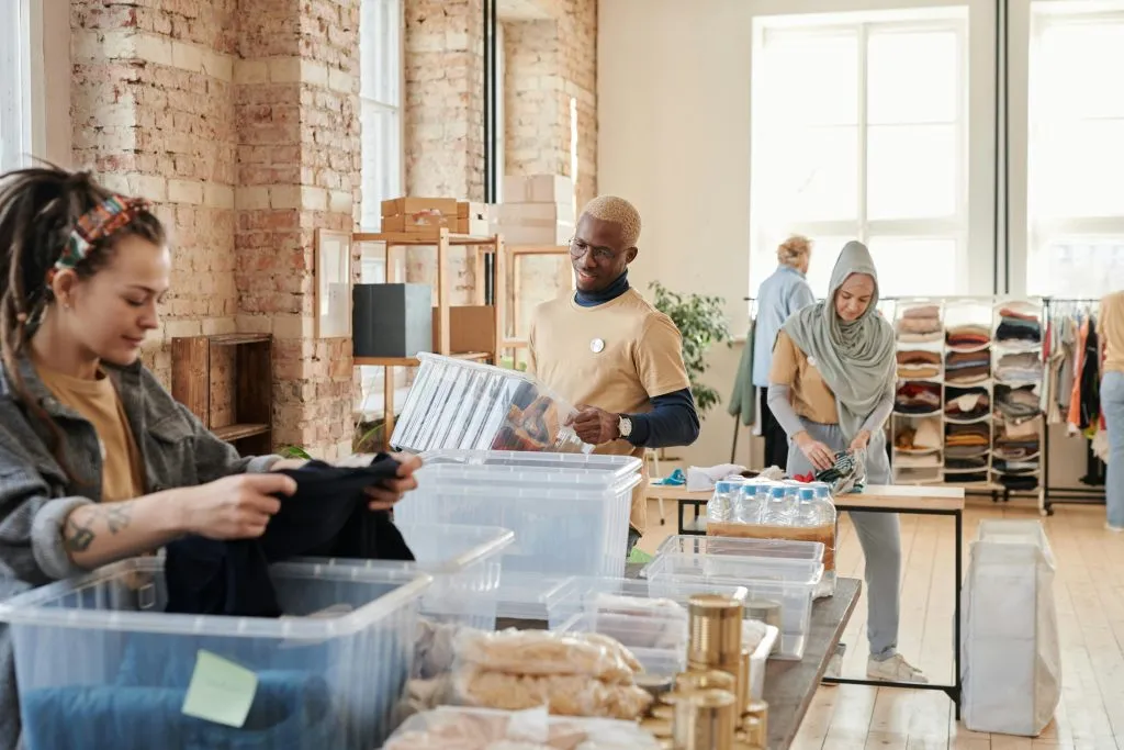 Volunteers organize donations, including clothes and food, in a bright, spacious community center.