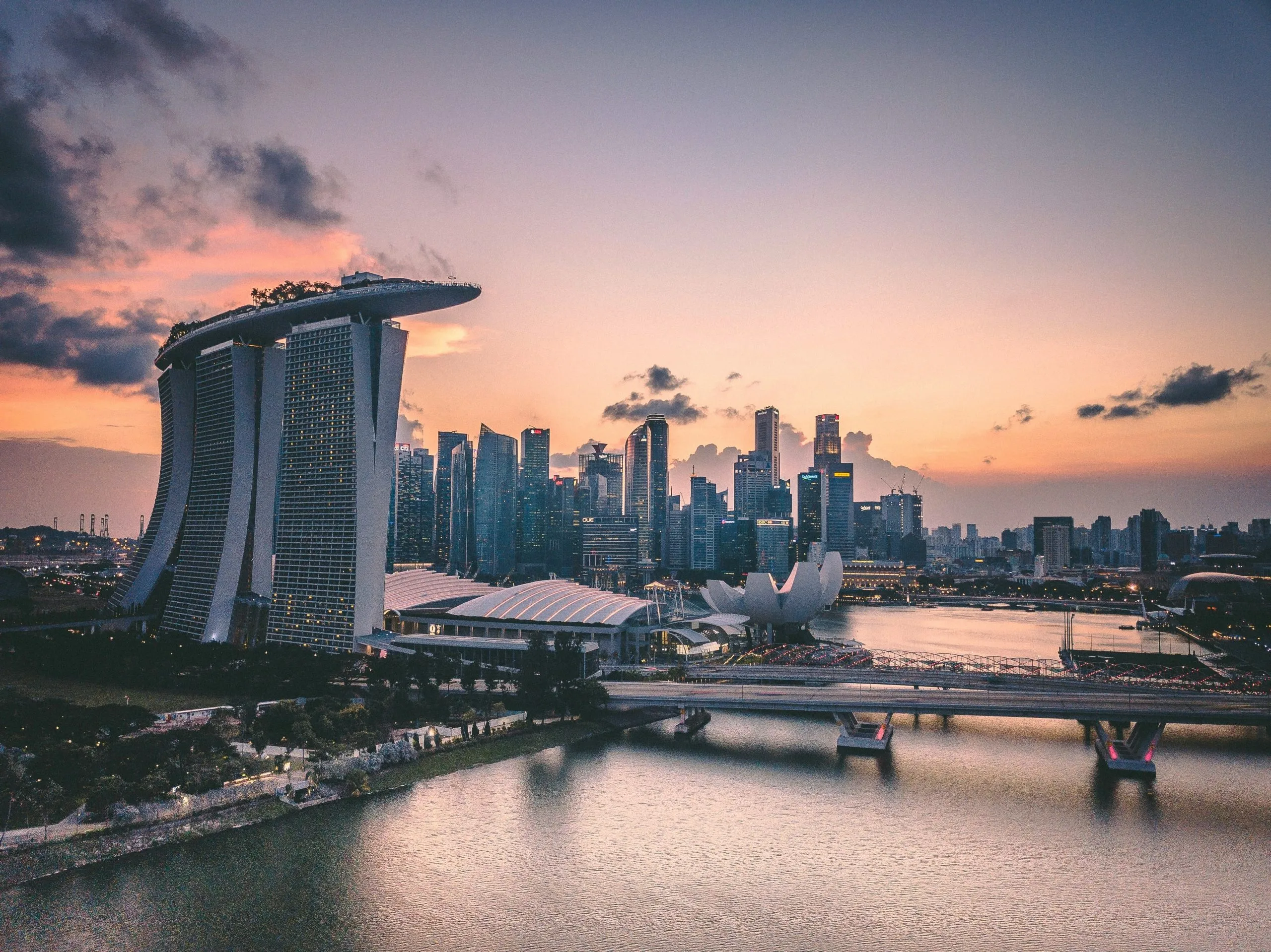 Singapore skyline at sunset featuring Marina Bay Sands and the ArtScience Museum by the waterfront.