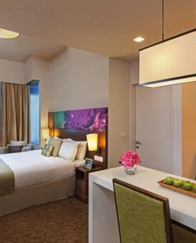 Modern hotel room with a cozy bed, vibrant decor, and a small dining area.