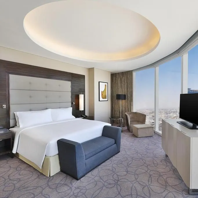 Elegant hotel room with modern decor, large windows, and a circular recessed ceiling light.