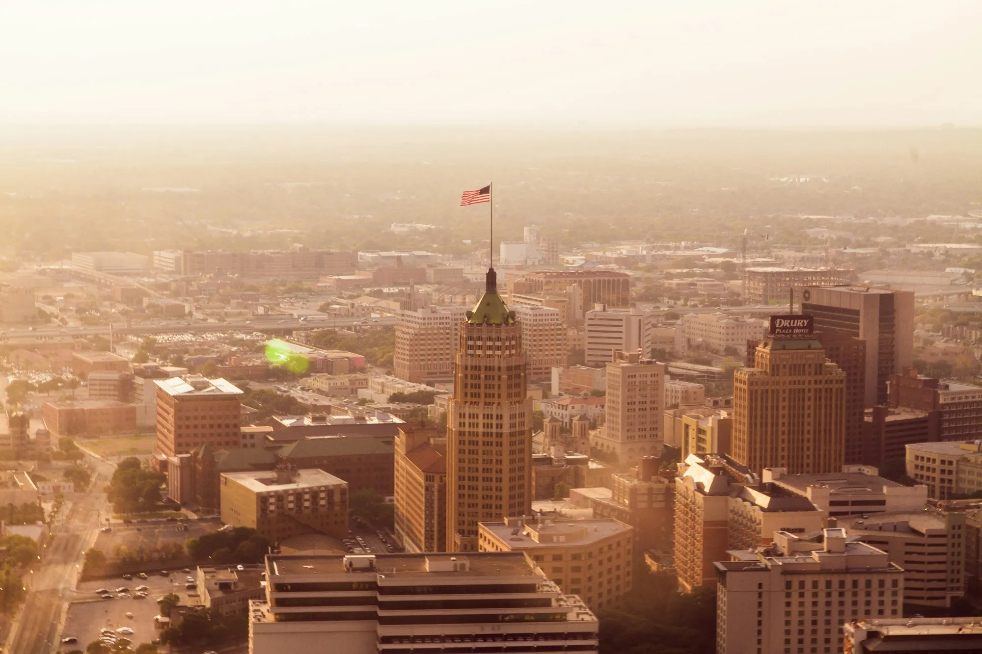 A hazy aerial view of downtown San Antonio, Texas, featuring the iconic Tower Life Building.