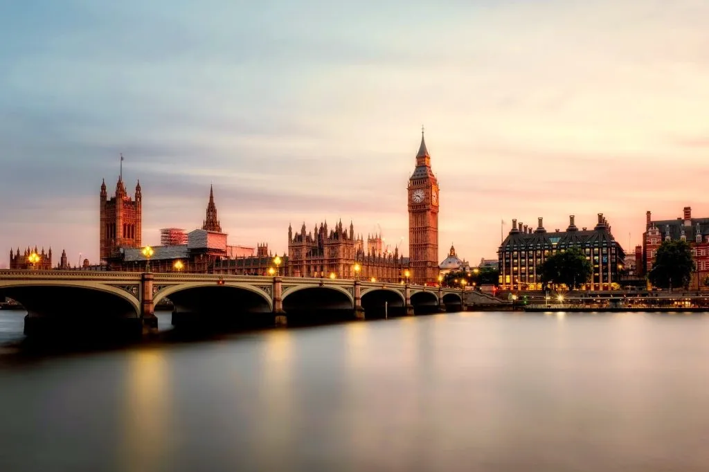 Big Ben and Westminster Bridge at sunset, reflecting over the River Thames in London.