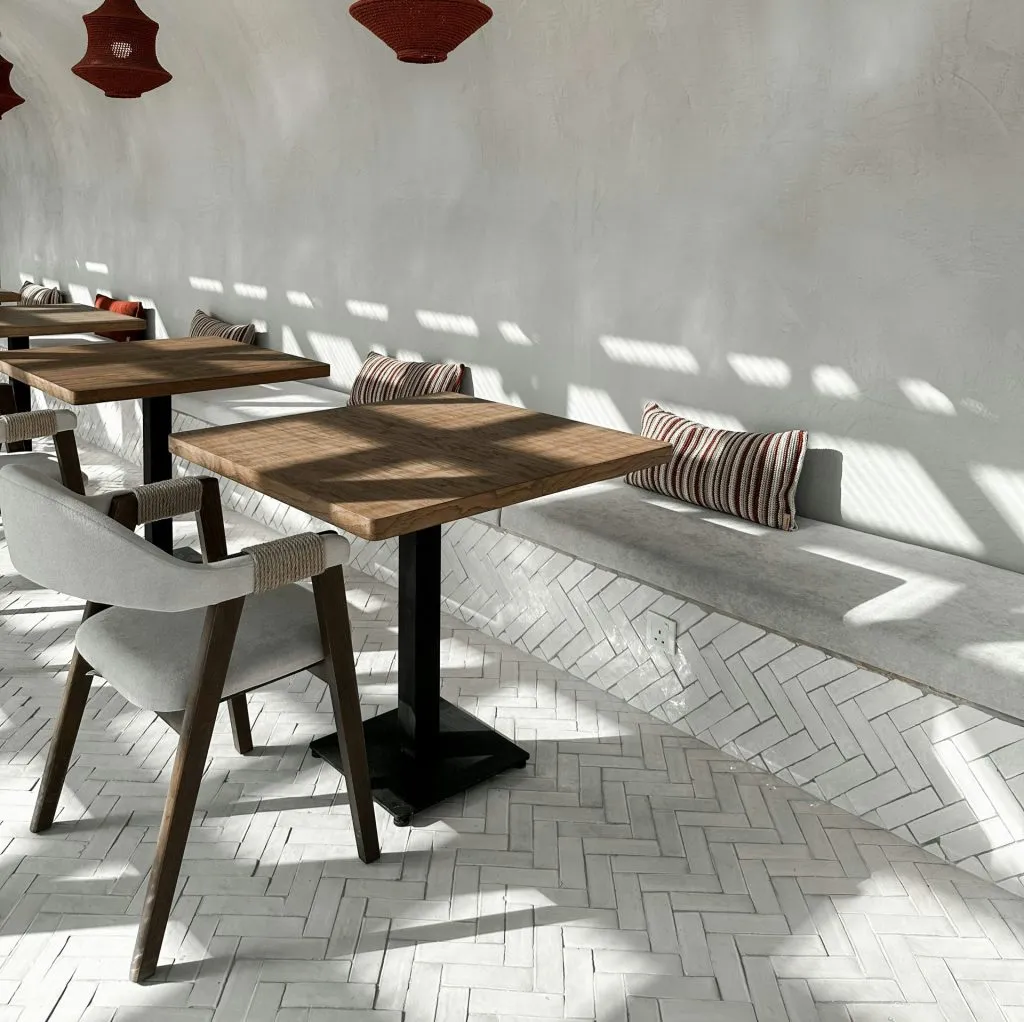 Minimalist seating area with wooden tables, modern chairs, and herringbone tile accents.