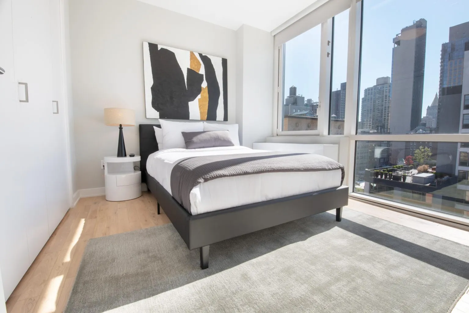 Modern bedroom with minimalist decor, large windows, and cityscape views.