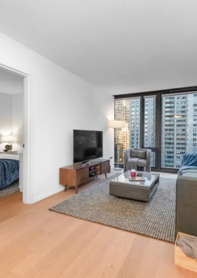 Modern living room with city views, sleek furniture, and natural light from large windows.