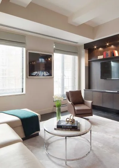 Modern living room with neutral tones, sleek furniture, and natural light from large windows.