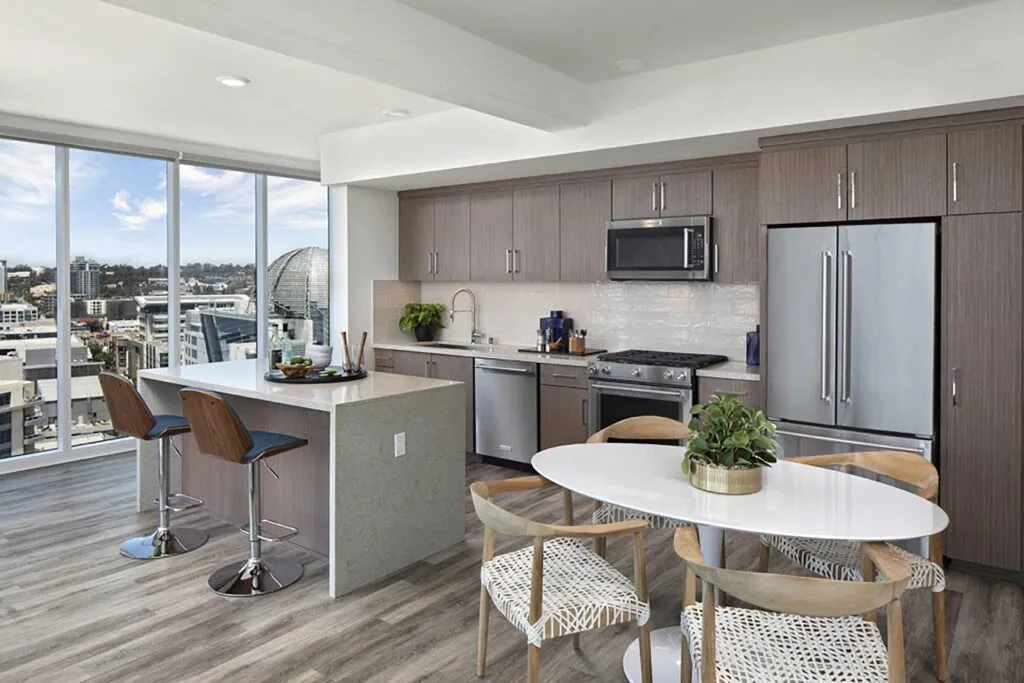 Modern kitchen with city views, sleek cabinetry, island seating, and a stylish dining area.