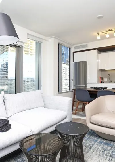 Modern apartment interior with sleek furniture, large windows, and a compact kitchen area.