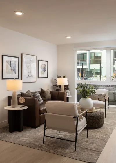Modern living room with neutral tones, leather sofa, accent chairs, and minimalist decor.
