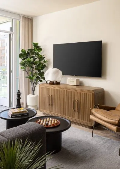 Modern living room with neutral tones, a wall-mounted TV, and stylish furniture accents.