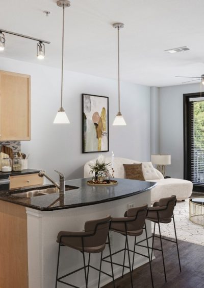 Modern kitchen and living area with pendant lighting, bar seating, and neutral decor.