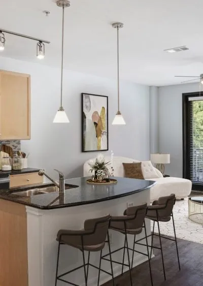 Modern kitchen and living area with pendant lighting, bar seating, and neutral decor.