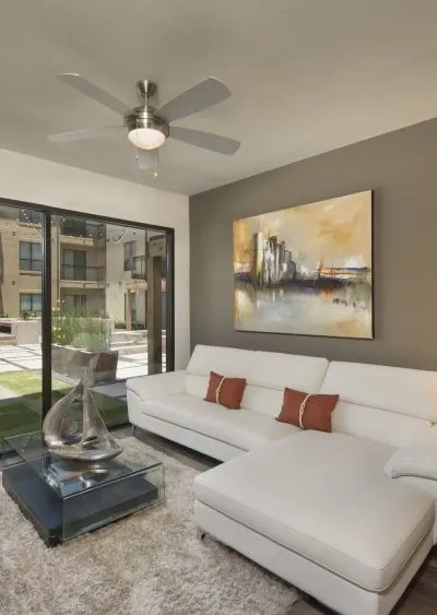 Modern living room with white sectional sofa, abstract art, and glass doors to outdoor space.