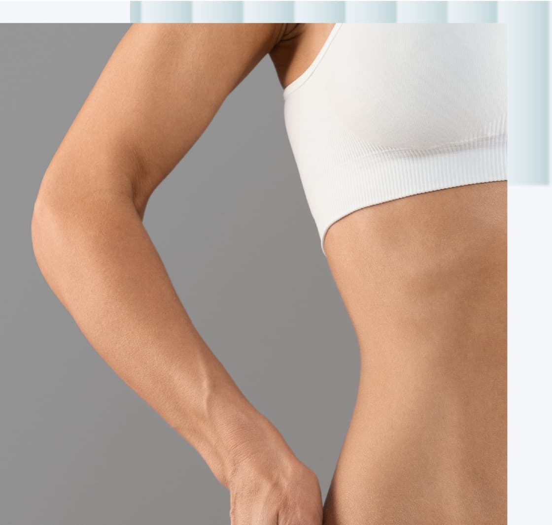 A close-up of a woman's arm and torso, with the arm positioned at the waist. The skin tone is a natural shade, and she is wearing a white crop top.