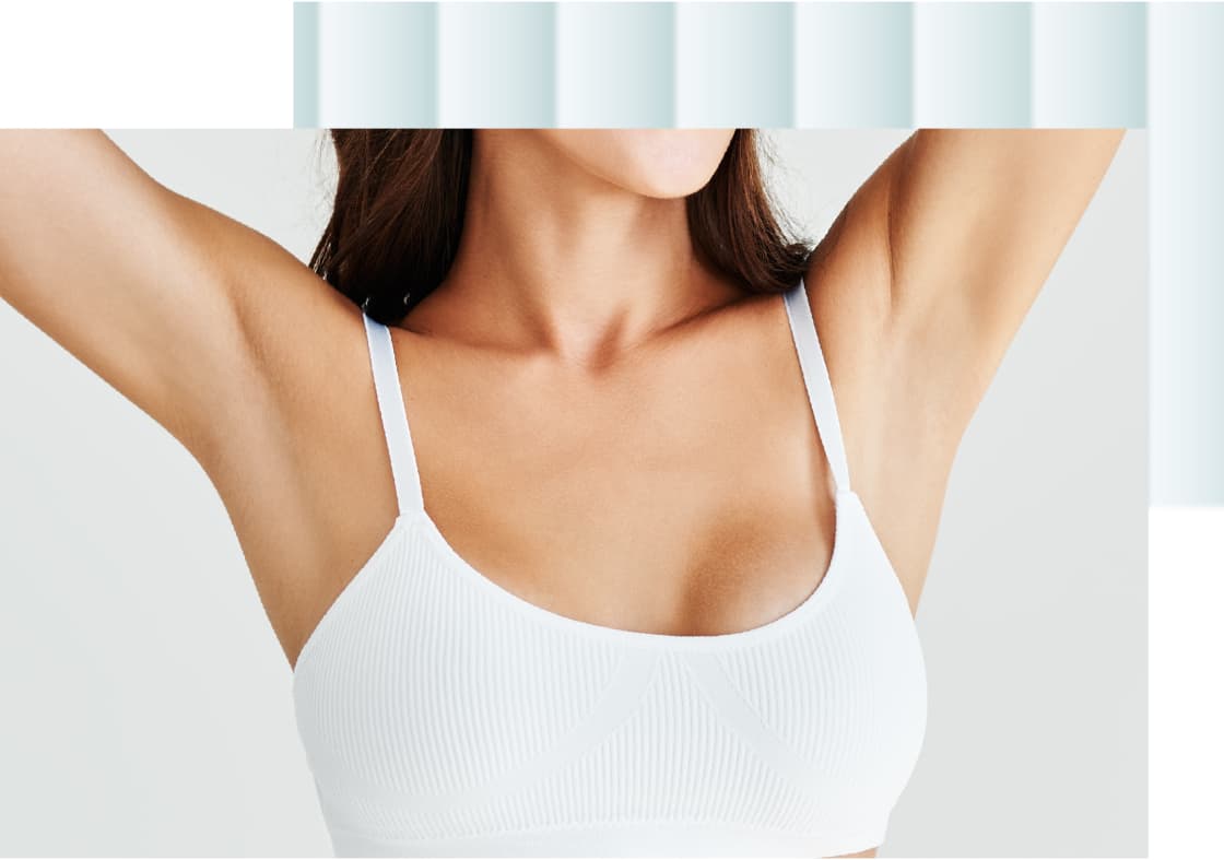 A woman is wearing a white, ribbed bralette with thin straps, showing her shoulders and upper torso.