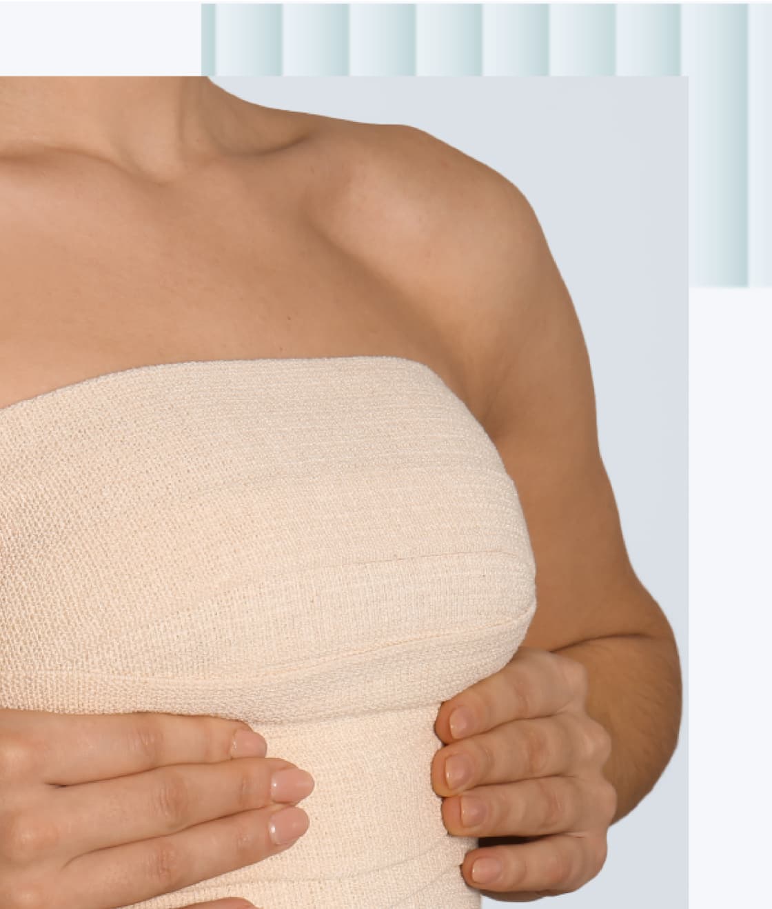 A woman holding her hands together in front of her chest while wearing a strapless beige top.