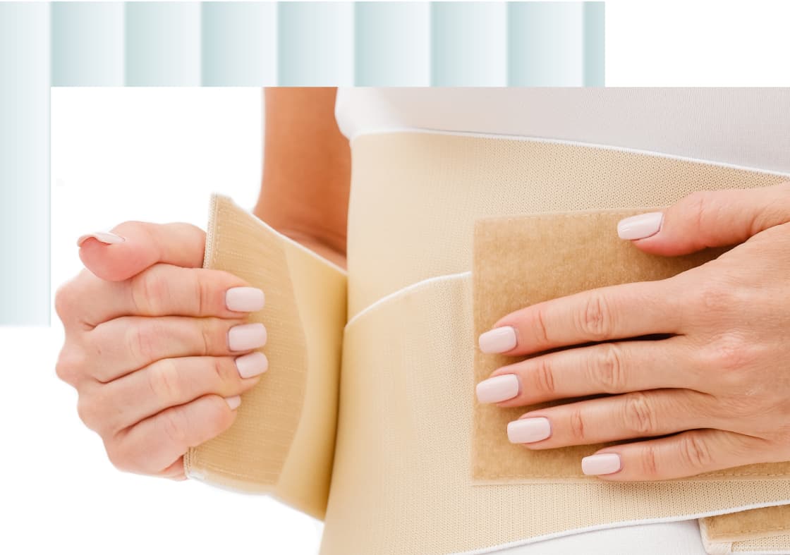 A person's hands adjusting a beige abdominal support brace, with one hand holding the brace while the other presses a patch against it.