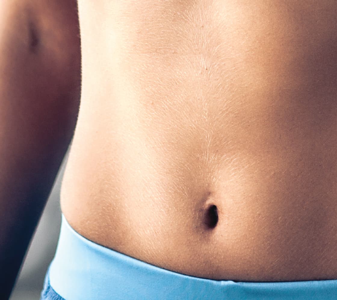 An image of a person's abdomen featuring smooth skin, with a visible belly button and a light blue waistband.