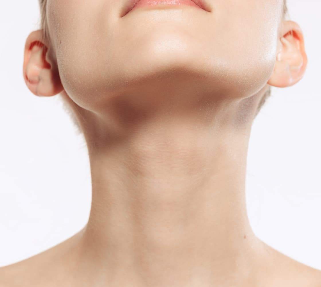 A close-up image of a person's neck and chin area, showcasing smooth skin and a subtle upward gaze.