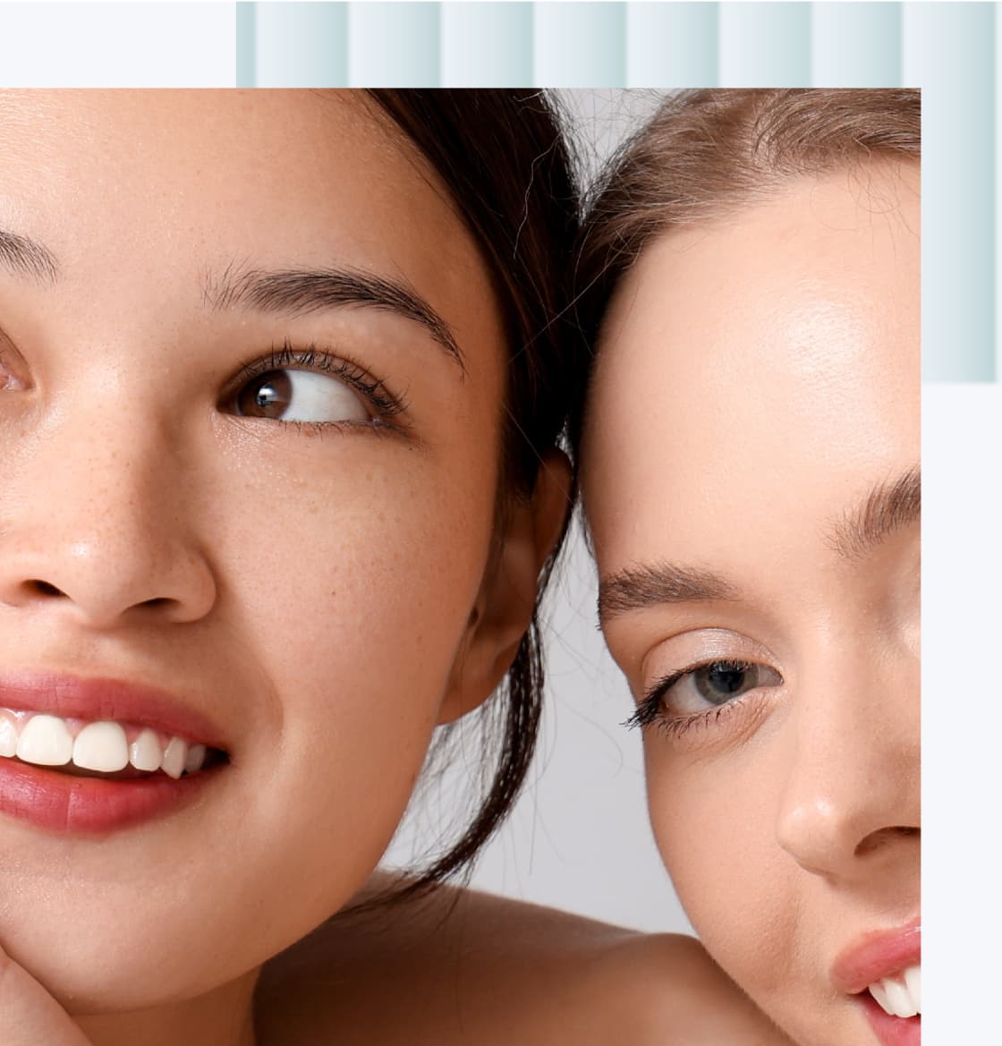 Two young women with smiles, one with light brown skin and dark hair, the other with fair skin and light brown hair, both showing their teeth and displaying friendly expressions.