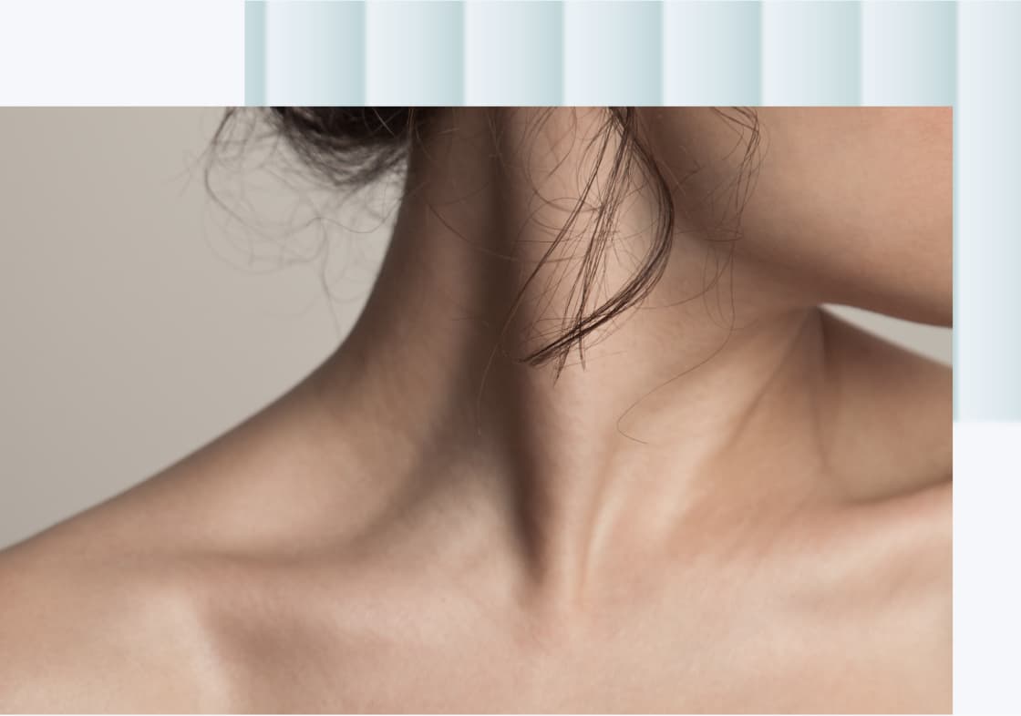 A close-up of a woman's neck and shoulder area, showcasing smooth skin and a delicate hairstyle with loose strands of hair.
