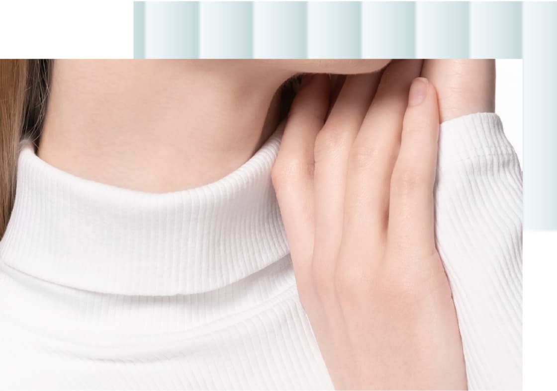 A close-up of a person's neck and chin, with one hand gently touching the neck, wearing a white turtleneck top.